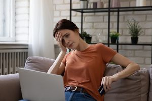 An upset woman looking at computer screen. Consumer fraud occurs when an entity uses deceptive business practices