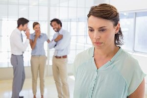 Racial discrimination in the workplace. Colleague gossiping and a woman is on the foreground