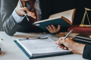 client signs a document while the attorney talks about the personal injury trial