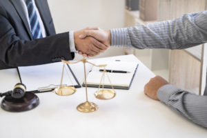 lawyer and client shake hands before talking about handling of settlement dispute regarding a car accident