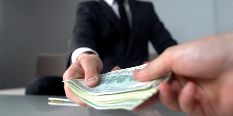 lawyer hands one of the settlements money in cash to the client of the personal injury case