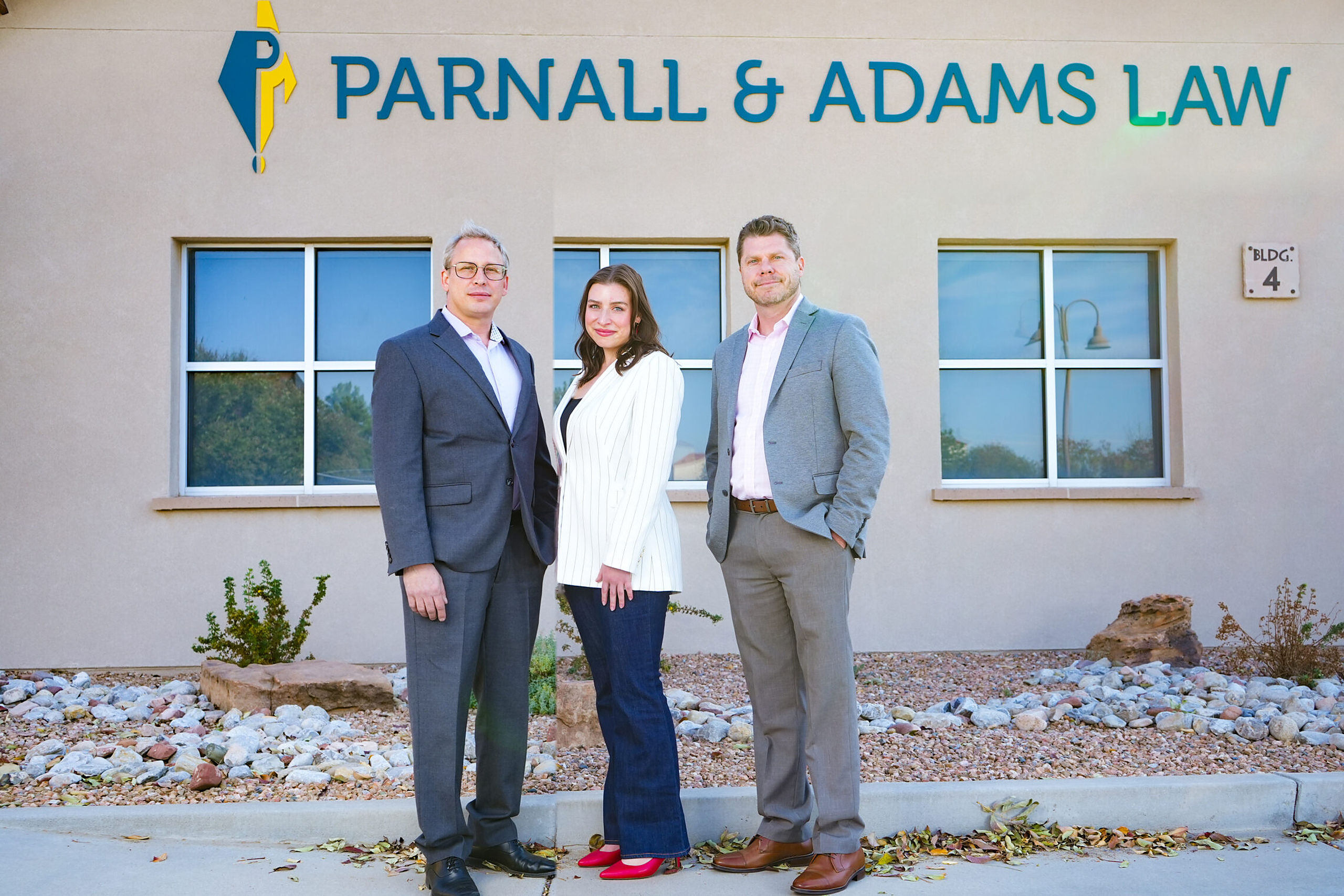 Attorneys Charles Parnall, David Adams, Mallory Wolff, and their team of paralegals, law clerks, and receptionists standing in front of their office, ready to act as informed attorneys in Albuquerque, NM.